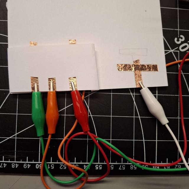 I went back to the copper tape to create a button-like design with raised paper. The white clip acted as my ground, and one had to hold it down then press on one of the clips to activate the Makey Makey.